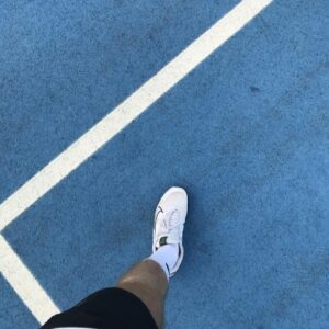 Close-up of a sneaker on a vibrant blue tennis court in Gölcük, Türkiye. Perfect for sports themes.