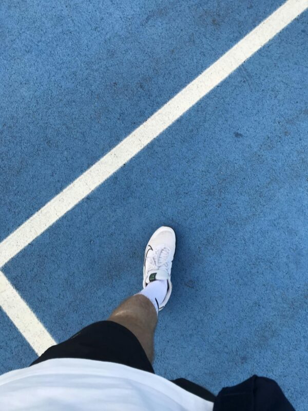 Close-up of a sneaker on a vibrant blue tennis court in Gölcük, Türkiye. Perfect for sports themes.