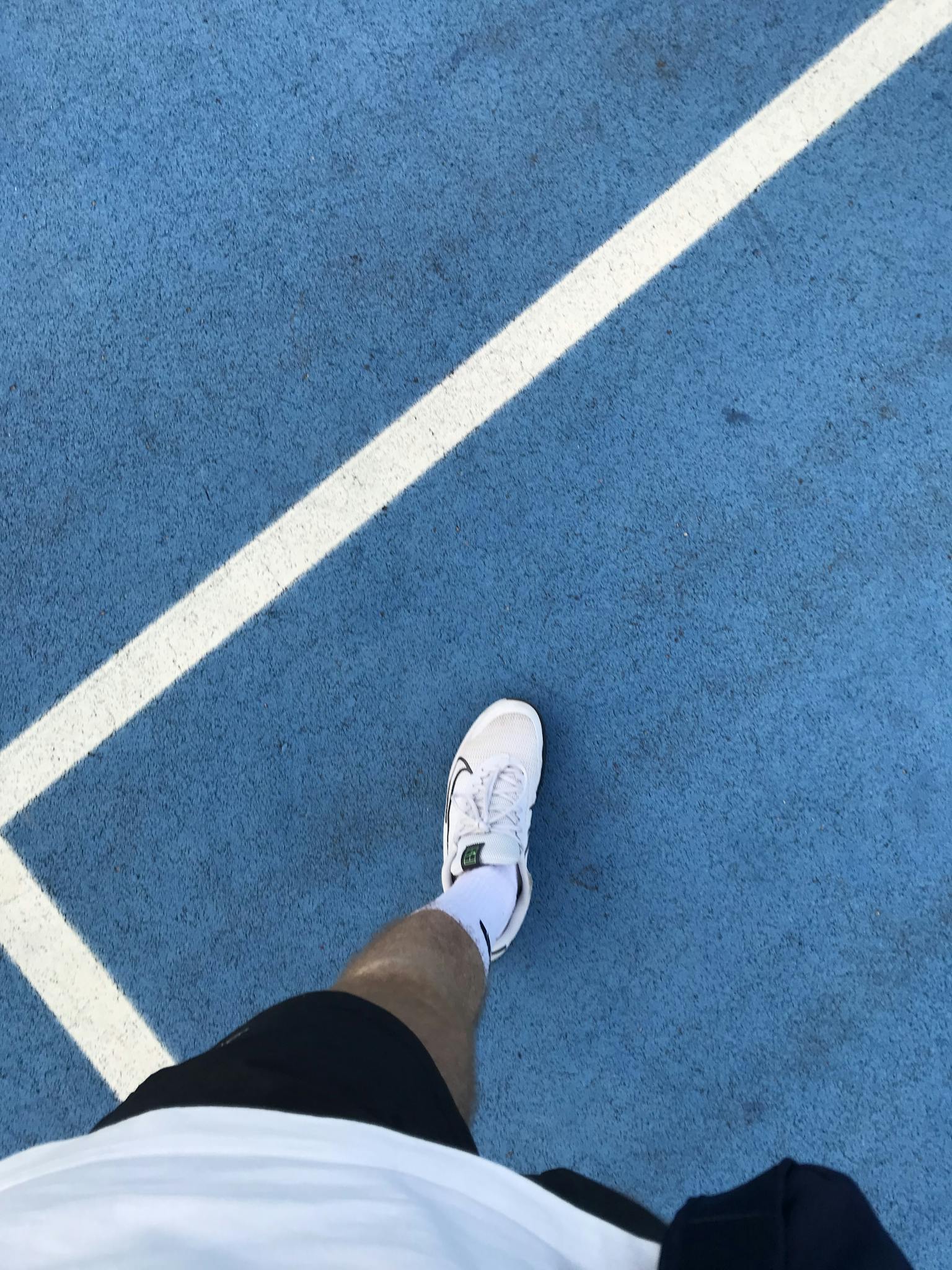 Close-up of a sneaker on a vibrant blue tennis court in Gölcük, Türkiye. Perfect for sports themes.